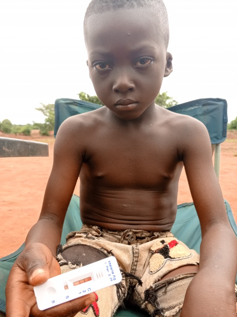 ヤウ・ボアテンくんがマラリア迅速検査キットを手に持つ様子（陽性の表示）